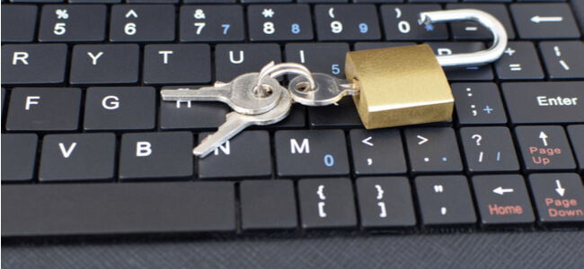 Golden unlocked padlock on black computer laptop or tablet keyboard.